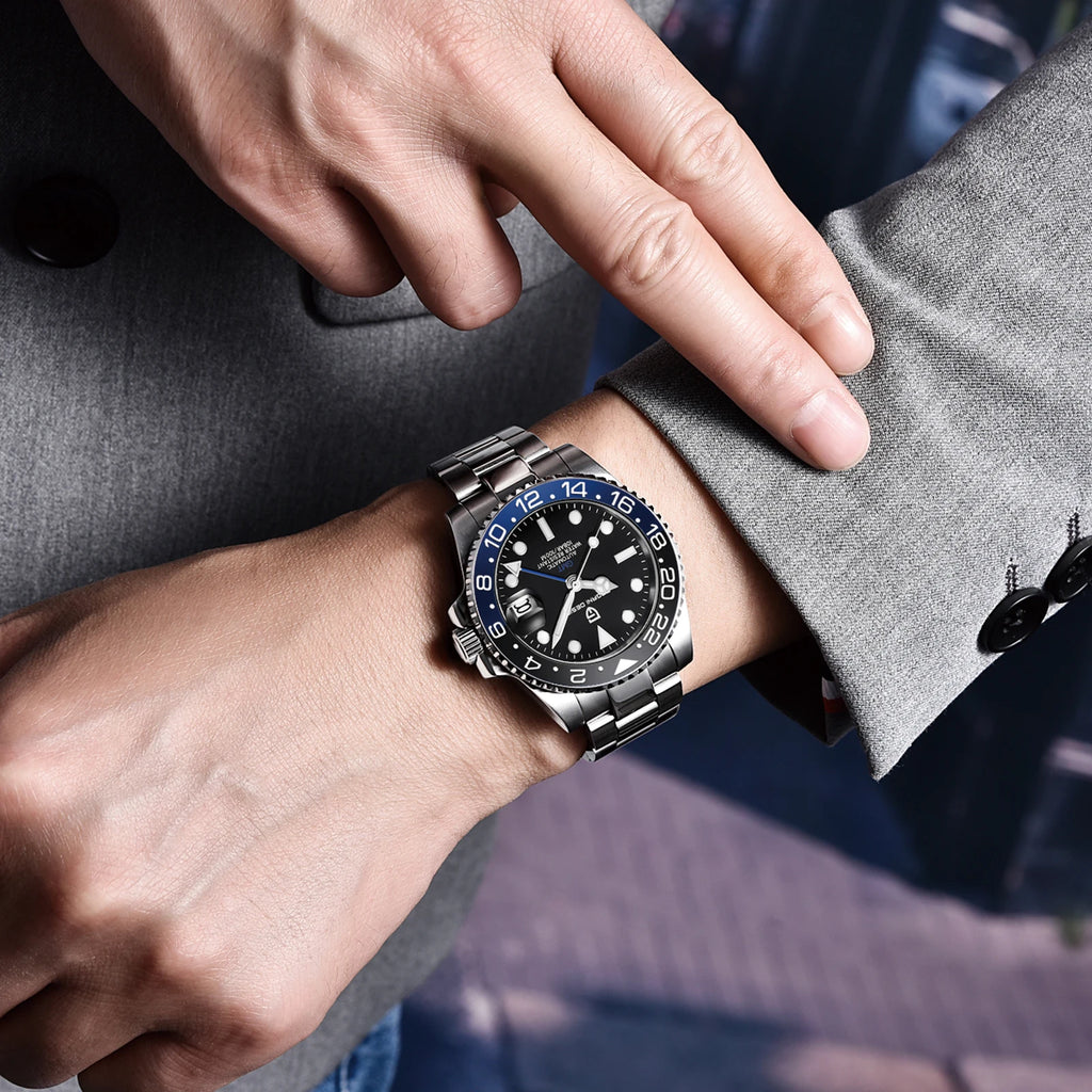 Person wearing a silver watch with a black face on a gray sleeve.