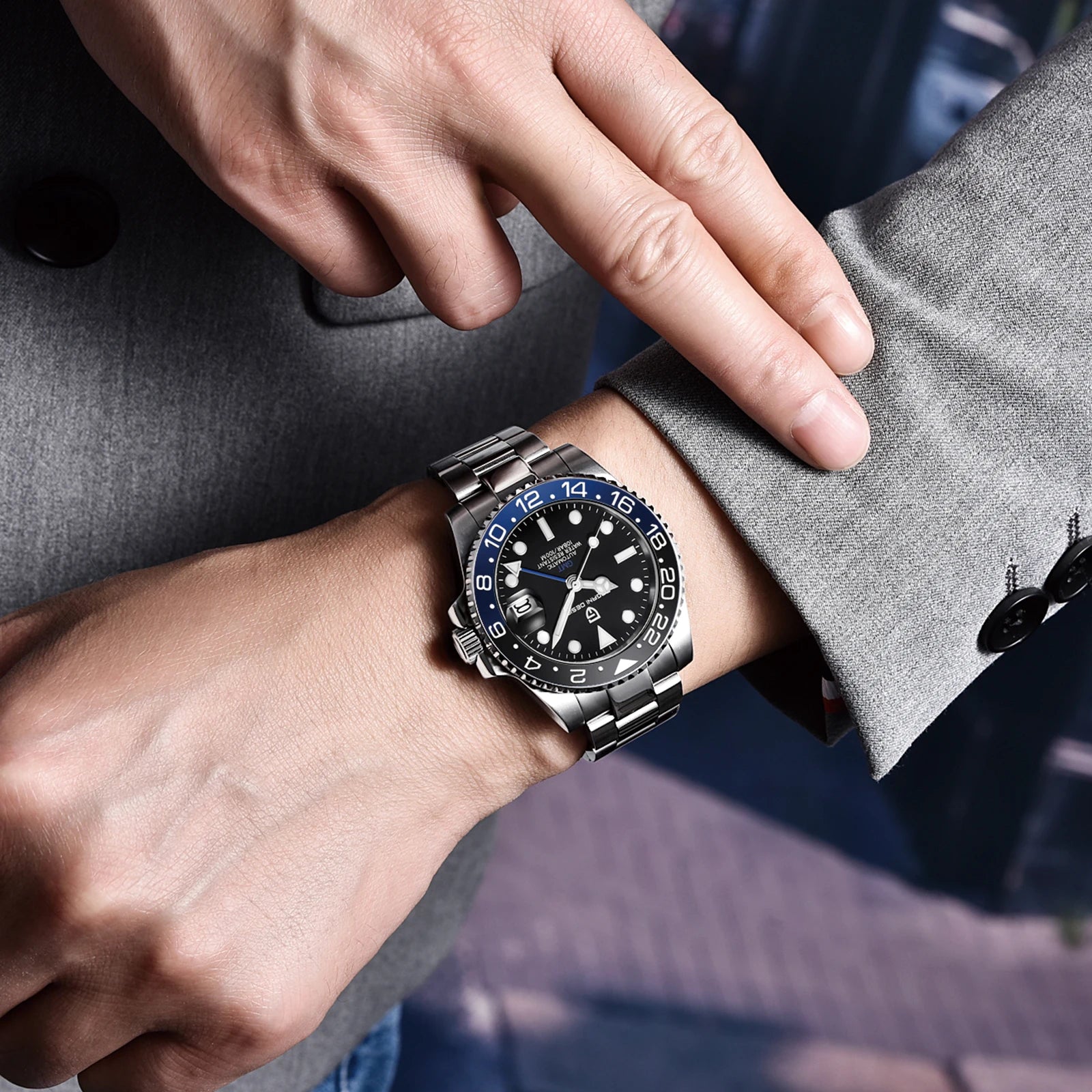 Person wearing a silver watch with a black face on a gray sleeve.