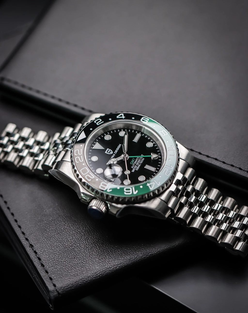 Silver watch with a black face and green accents on a dark surface